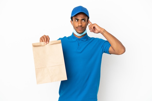 Uomo afroamericano che prende un sacchetto di cibo da asporto isolato su sfondo bianco con dubbi e pensieri