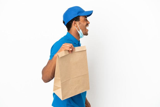 Photo african american man taking a bag of takeaway food isolated on white background laughing in lateral position