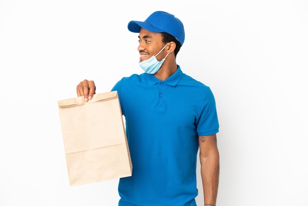 African American man taking a bag of takeaway food isolated on white background looking side