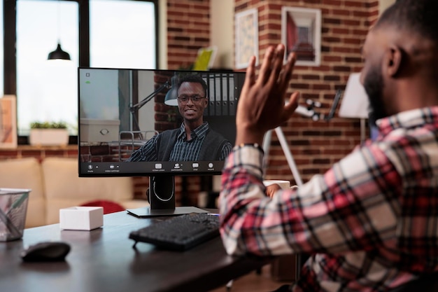 Uomo afroamericano che parla in videoconferenza, incontro con il collega in chat di teleconferenza online con webcam sul computer. utilizzo della videoconferenza remota su internet, lavoro da remoto.