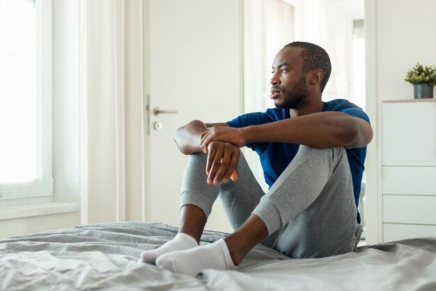 African American Man Thinking About Problems Having Depression In Bedroom