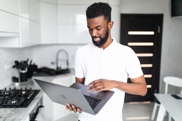 Афро-американский мужчина с помощью ноутбука на кухне