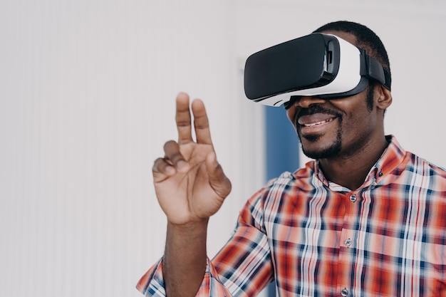 Афроамериканец в очках виртуальной реальности взаимодействует с киберпространством, играет в онлайн-видеоигру