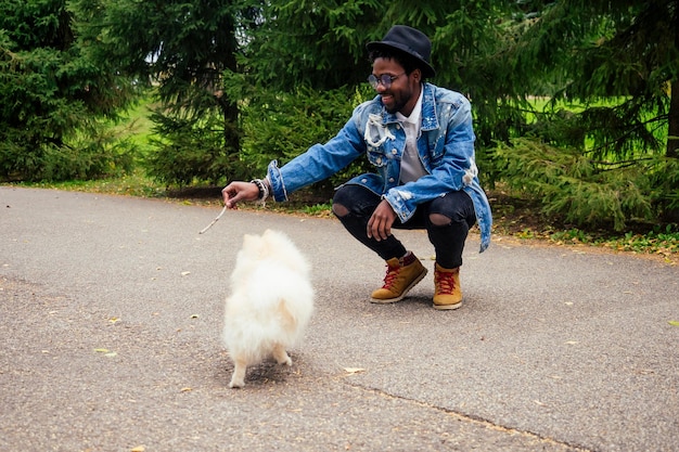 African american man walking in street with his fluffy spitzteaching education dog teams