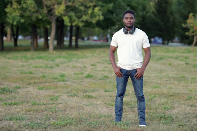 African american man walks in green city park on lawn