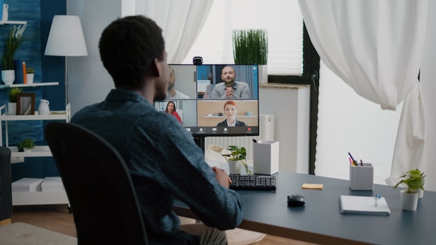 African american man waving to colleagues talking on online conference internet call