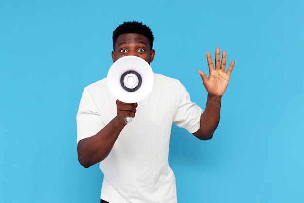 african american man in white tshirt announces information into loudspeaker on blue background