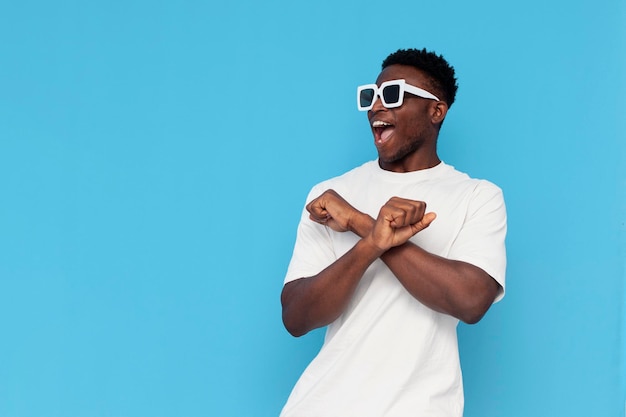 African american man in white tshirt and sunglasses dances to music and sings on blue background