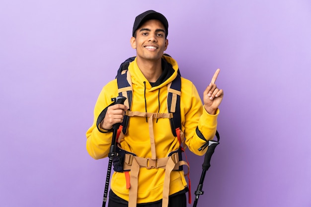 African american man with backpack and trekking poles over isolated wall showing and lifting a finger in sign of the best