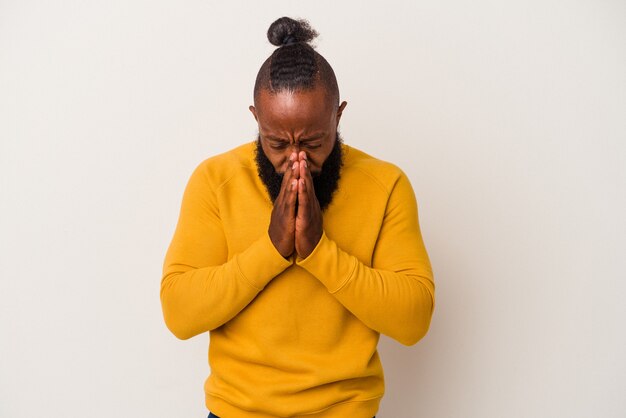 African american man with beard isolated on pink background praying, showing devotion, religious person looking for divine inspiration.