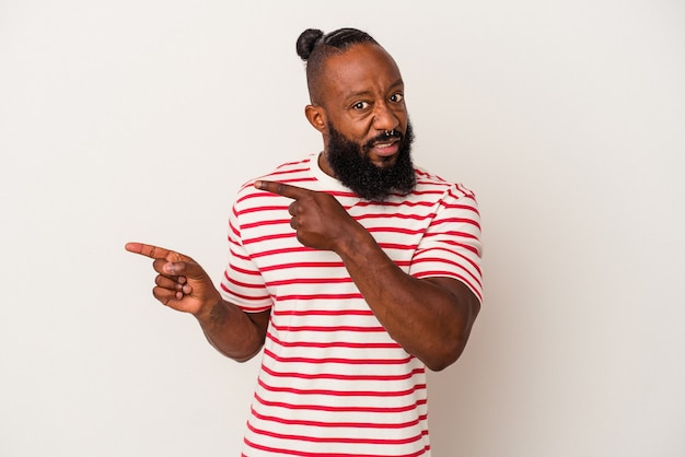 African american man with beard isolated on pink wall shocked pointing with index fingers to a copy space.