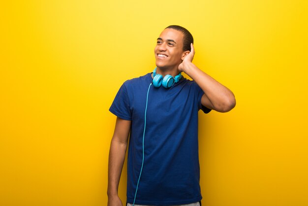 African american man with blue t-shirt on yellow background thinking an idea while scratching head