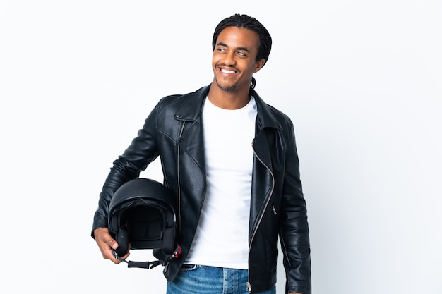 African American man with braids holding a motorcycle helmet isolated on white background thinking an idea while looking up