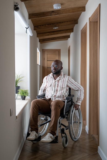 African american man with disability sitting on wheelchair in corridor
