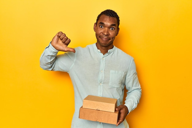 Афроамериканский мужчина с коробками с едой, показывающий жест неприязни, пальцем вниз концепция несогласия