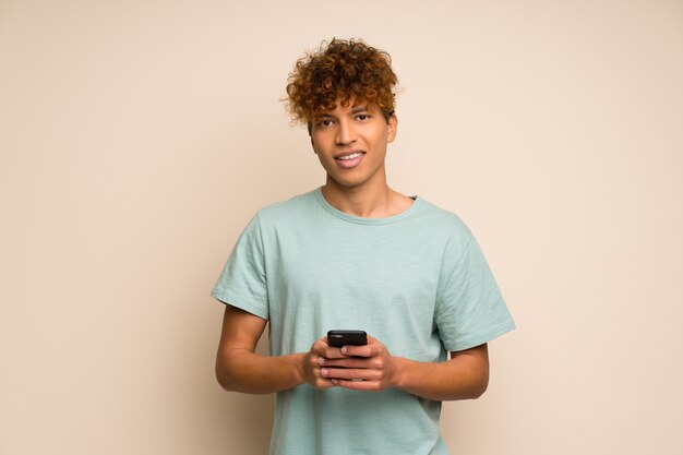 Photo african american man with green shirt sending a message with the mobile