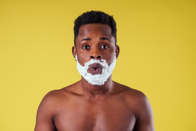 African-american man with razor and shaving foam on his face