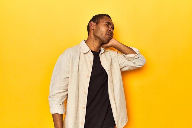 African American man with shirt yellow studio having a neck pain due to stress