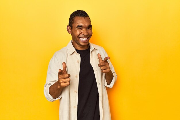 African American man with shirt yellow studio pointing to front with fingers