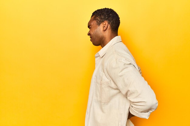 Photo african american man with shirt yellow studio suffering a back pain