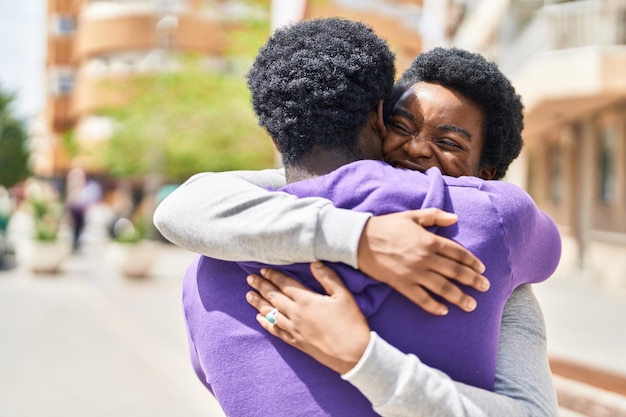 Foto coppie dell'uomo e della donna dell'afroamericano che sorridono fiduciosi che si abbracciano alla via