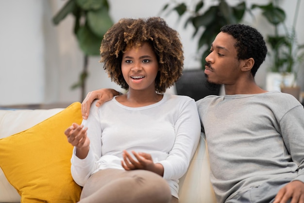 African american man and woman sitting on couch talking