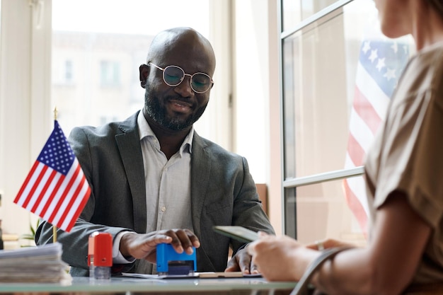 African american manager putting seals in documents to make visa documents for client in office