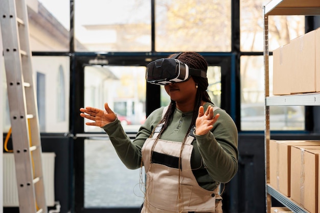 African american manager wearing virtual reality goggles, enjoying storehouse simulation, preparing clients orders in warehouse. African american employee working at goods inventory in storage room