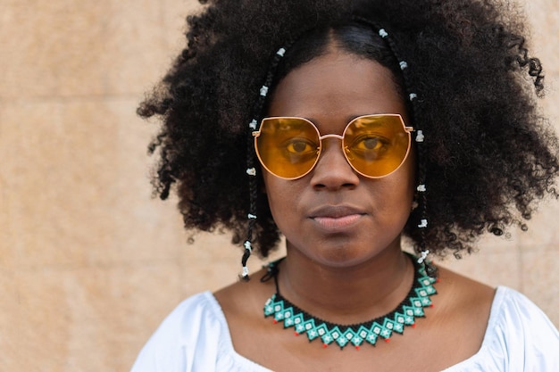 African American model with afro hairstyle with fashion glasses looking at the camera while standing on the street