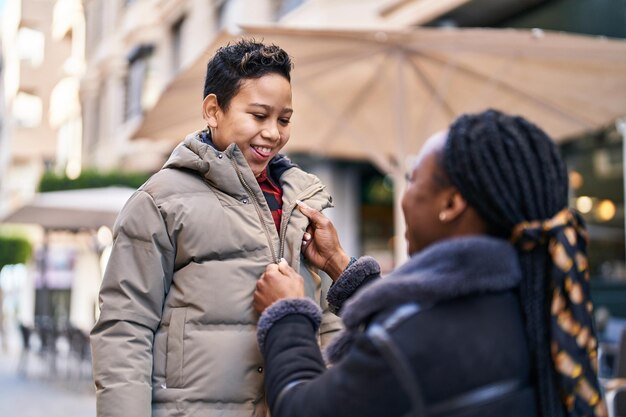 African american mother and son smiling confident closing jacket at street