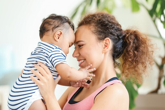 African-American mother training with cute little baby at home