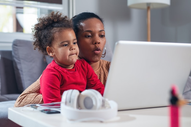 African American mother with little daughter using laptop together