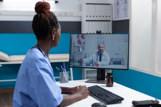 African american nurse explaining sickness symptoms to remote doctor