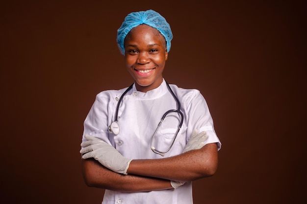 Ragazza infermiera afroamericana che indossa uniforme medica e stetoscopio su sfondo marrone eccitata per il successo