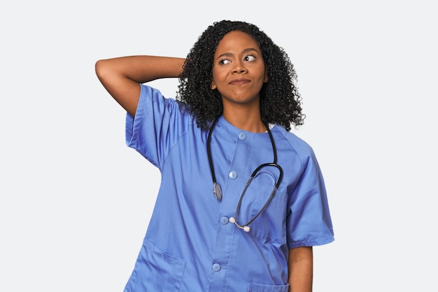 African American nurse in studio background touching back of head thinking and making a choice