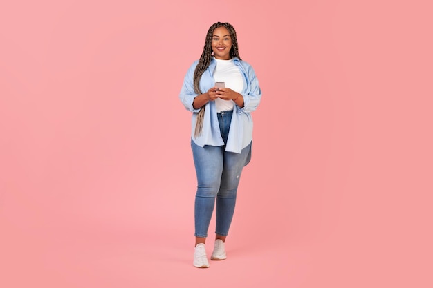 African American Overweight Lady Using Cellphone Standing Over Pink Background