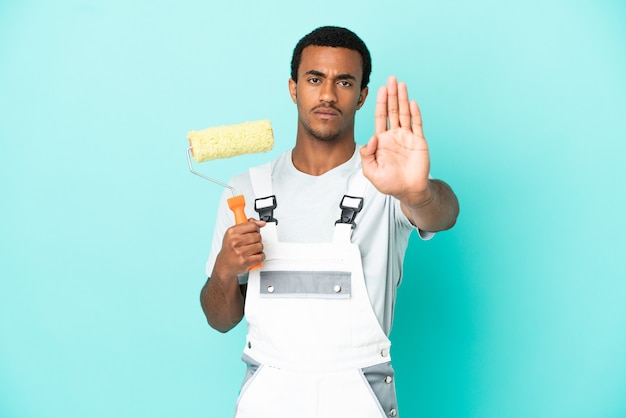 Photo african american painter man over isolated blue background making stop gesture