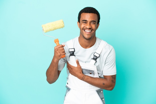 African American painter man over isolated blue background smiling a lot