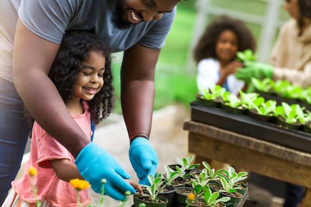 African American parents teaching children to take care of plants at plant nursery