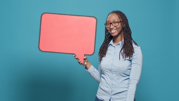 African american person holding mockup speech bubble on\
cardboard to put text messages and notes. using isolated copyspace\
with carton board to advertise information in front of camera.