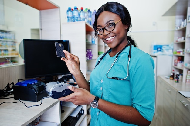 Farmacista afroamericano che lavora in farmacia presso la farmacia ospedaliera assistenza sanitaria africana lavora con terminale di pagamento e carta di credito