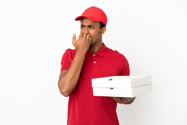 African American pizza delivery man picking up pizza boxes over isolated white wall having doubts