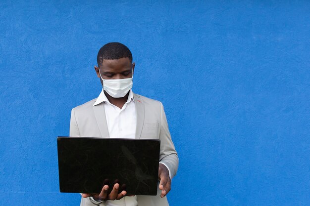  African American in a protective mask with a laptop in his hand