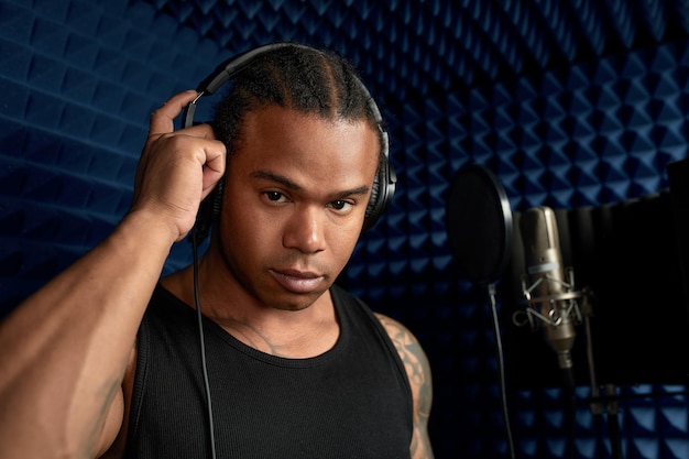 Photo african american at the recording studio in headphones reads rap