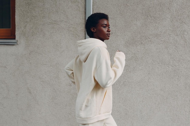 African American runner woman in hoodie jogging outdoors.