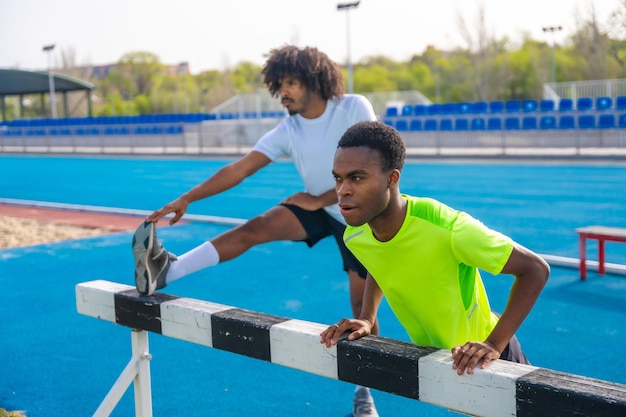 アフリカ系アメリカ人のランナーがランニングトラックで伸びています