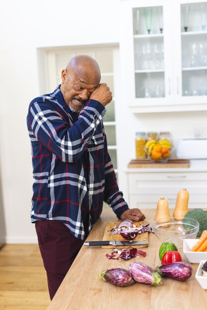 Photo african american senior man preparing vegetables chopping onions in kitchen