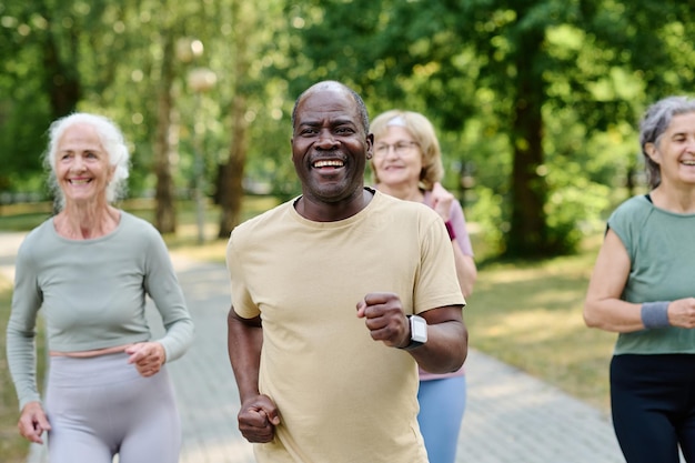 Photo african american senior man running together with other senior people in the park