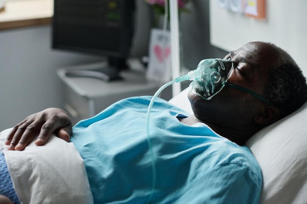 african american senior patient lying with oxygen mask during treatment in hospital ward
