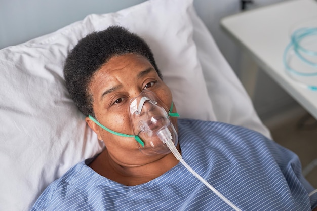 African American senior woman in hospital room looking at camera oxygen support